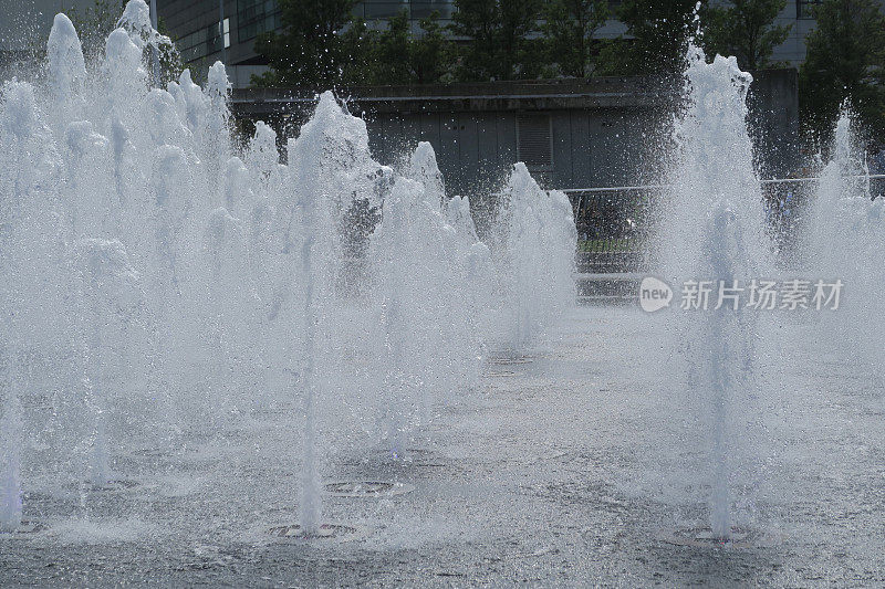 公园花园铺路板上的路面喷水池/湿砖铺路水景，喷水池的水溅在铺路石上，让孩子们在夏天玩耍和淋湿，多个喷水池和水滴倾泻而下